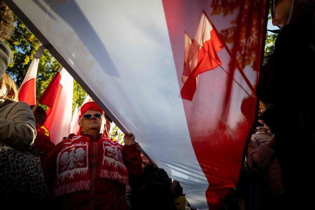 Participants hold Poland's national flags during an anti-government demonstration in front of the Constitutional Court in Warsaw on October 17, 2026. Right wing demonstrators hold a camp protest outside the building of the Constitutional Court in Poland in protest against the nomination of new judges and in defence of those appointed by the previous government of the Law and Justice Party (PiS). (Photo by Wojtek RADWANSKI / AFP)