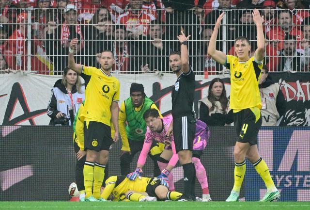 Dortmund's players gesture to the medics after one of their teammates was injured during the German first division Bundesliga football match between Union Berlin and Borussia Dortmund in Berlin on October 17, 2026. (Photo by John MACDOUGALL / AFP) / DFL REGULATIONS PROHIBIT ANY USE OF PHOTOGRAPHS AS IMAGE SEQUENCES AND/OR QUASI-VIDEO