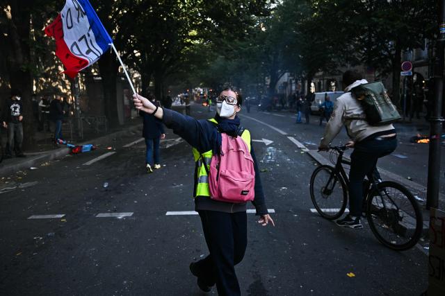 A protester wearing a yellow vest waves a French flag during a demonstration to protest against the "high cost of living", in Bordeaux, southwestern France, on October 17, 2026 as part of a nationwide call for mobilisation bringing together various groups expressing their anger: former "Yellow Vest", secondary school and university students, climate activists and even farmers. After weeks of student protests, France faces broader, nationwide demonstrations on October 17, 2026 over the cost of living, setting up a potentially fraught six months heading into a presidential election. A police source told AFP that authorities estimated nearly 200,000 people could take part, with 40,000 in Paris. (Photo by Christophe ARCHAMBAULT / AFP)