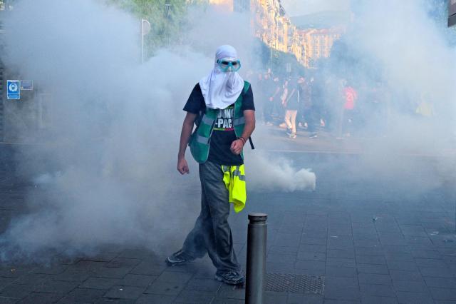A protester wearing goggles and a Balaclava walks amid the smoke from a teargas fired by the police during a demonstration to protest against the "high cost of living", in Nice, southern France, on October 17, 2026 as part of a nationwide call for mobilisation bringing together various groups expressing their anger: former "Yellow Vest", secondary school and university students, climate activists and even farmers. After weeks of student protests, France faces broader, nationwide demonstrations on October 17, 2026 over the cost of living, setting up a potentially fraught six months heading into a presidential election. A police source told AFP that authorities estimated nearly 200,000 people could take part, with 40,000 in Paris. (Photo by Valery HACHE / AFP)