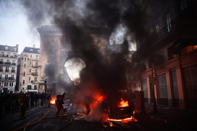 Firefighters extinguish a car on fire near the Porte Saint-Denis during a demonstration to protest against the "high cost of living", in Paris on October 17, 2026 as part of a nationwide call for mobilisation bringing together various groups expressing their anger: former "Yellow Vests", secondary school and university students, climate activists and even farmers. After weeks of student protests, France faces broader, nationwide demonstrations on October 17, 2026 over the cost of living, setting up a potentially fraught six months heading into a presidential election. A police source told AFP that authorities estimated nearly 200,000 people could take part, with 40,000 in Paris. (Photo by Kiran RIDLEY / AFP)