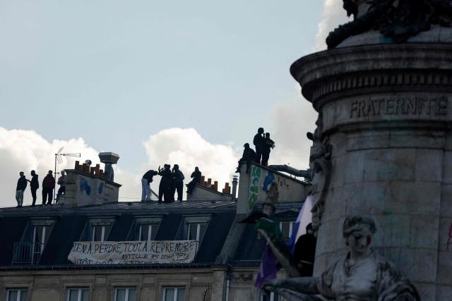 Protesters stand on roofs next to a banner reading "Nothing to lose, Everything to redo" behind the 'Statue de la Republique' during a demonstration against the "high cost of living", in Paris on October 17, 2026 as part of a nationwide call for mobilisation bringing together various groups expressing their anger: former "Yellow Vest", secondary school and university students, climate activists and even farmers. After weeks of student protests, France faces broader, nationwide demonstrations on October 17, 2026 over the cost of living, setting up a potentially fraught six months heading into a presidential election. A police source told AFP that authorities estimated nearly 200,000 people could take part, with 40,000 in Paris. (Photo by GEOFFROY VAN DER HASSELT / AFP)