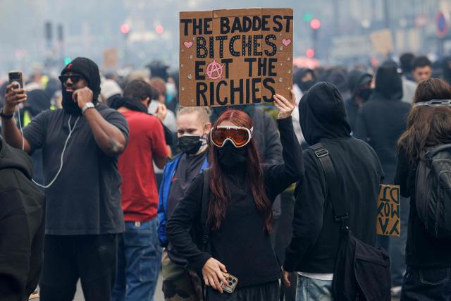 A protester holds a placard during a demonstration against the "high cost of living", in Paris on October 17, 2026 as part of a nationwide call for mobilisation bringing together various groups expressing their anger: former "Yellow Vest", secondary school and university students, climate activists and even farmers. After weeks of student protests, France faces broader, nationwide demonstrations on October 17, 2026 over the cost of living, setting up a potentially fraught six months heading into a presidential election. A police source told AFP that authorities estimated nearly 200,000 people could take part, with 40,000 in Paris. (Photo by GEOFFROY VAN DER HASSELT / AFP)