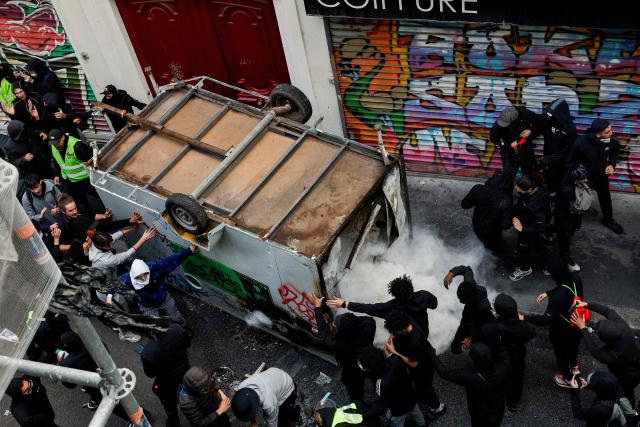 Protesters open a urban furniture during a demonstration against the "high cost of living", in Paris on October 17, 2026 as part of a nationwide call for mobilisation bringing together various groups expressing their anger: former "Yellow Vest", secondary school and university students, climate activists and even farmers. After weeks of student protests, France faces broader, nationwide demonstrations on October 17, 2026 over the cost of living, setting up a potentially fraught six months heading into a presidential election. A police source told AFP that authorities estimated nearly 200,000 people could take part, with 40,000 in Paris. (Photo by GEOFFROY VAN DER HASSELT / AFP)