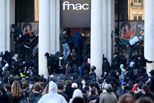 Protesters climb the fence of a fnac store during a demonstration against the "high cost of living", in Nantes, western France, on October 17, 2026 as part of a nationwide call for mobilisation bringing together various groups expressing their anger: former "Yellow Vest", secondary school and university students, climate activists and even farmers. After weeks of student protests, France faces broader, nationwide demonstrations on October 17, 2026 over the cost of living, setting up a potentially fraught six months heading into a presidential election. A police source told AFP that authorities estimated nearly 200,000 people could take part, with 40,000 in Paris. (Photo by Sebastien Salom-Gomis / AFP)