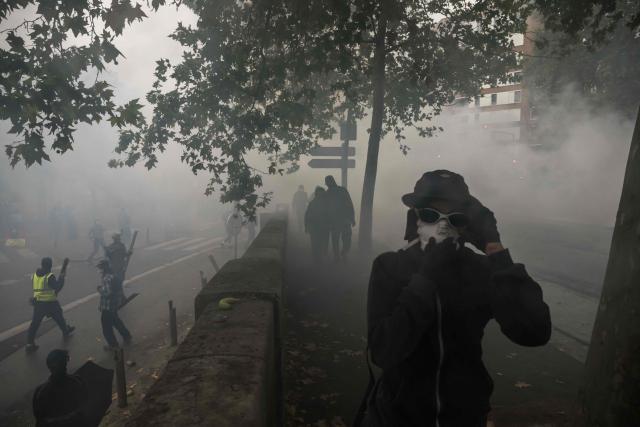 Protesters walk amid tear gas during a demonstration against the "high cost of living", in Toulouse, southwestern France, on October 17, 2026 as part of a nationwide call for mobilisation bringing together various groups expressing their anger: former "Yellow Vest", secondary school and university students, climate activists and even farmers. After weeks of student protests, France faces broader, nationwide demonstrations on October 17, 2026 over the cost of living, setting up a potentially fraught six months heading into a presidential election. A police source told AFP that authorities estimated nearly 200,000 people could take part, with 40,000 in Paris. (Photo by Ed JONES / AFP)