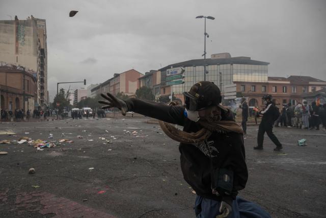 A protester launches a projectile towards French riot Police during a demonstration against the "high cost of living", in Toulouse, southwestern France, on October 17, 2026 as part of a nationwide call for mobilisation bringing together various groups expressing their anger: former "Yellow Vest", secondary school and university students, climate activists and even farmers. After weeks of student protests, France faces broader, nationwide demonstrations on October 17, 2026 over the cost of living, setting up a potentially fraught six months heading into a presidential election. A police source told AFP that authorities estimated nearly 200,000 people could take part, with 40,000 in Paris. (Photo by Ed JONES / AFP)