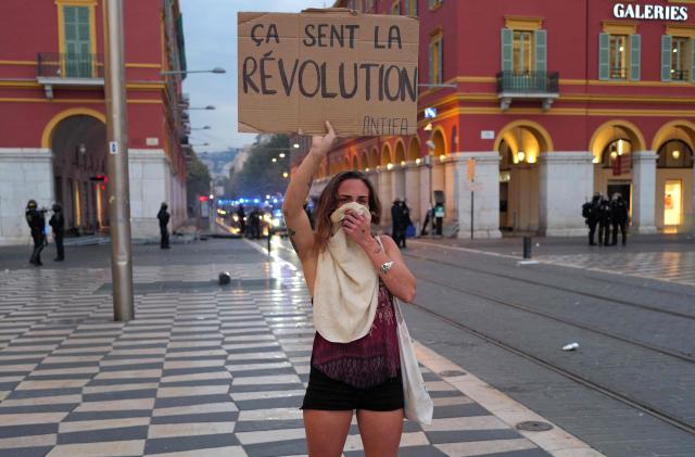 A protester holds a slogan reading "Smells like revolution" during a demonstration against the "high cost of living", at the Place Massana in Nice, southern France, on October 17, 2026 as part of a nationwide call for mobilisation bringing together various groups expressing their anger: former "Yellow Vest", secondary school and university students, climate activists and even farmers. After weeks of student protests, France faces broader, nationwide demonstrations on October 17, 2026 over the cost of living, setting up a potentially fraught six months heading into a presidential election. A police source told AFP that authorities estimated nearly 200,000 people could take part, with 40,000 in Paris. (Photo by Valery HACHE / AFP)