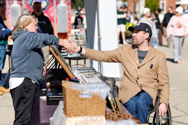 Democratic US Senate Candidate Josh Turek greets a member of the public during a campaign stop at the Dubuque Farmers Market in Dubuque, Iowa, on October 17, 2026. Turek is running to replace the retiring US Senator Joni Ernst. Americans voting in the November 3 midterm elections will decide who controls Congress for the final two years of Donald Trump's presidency, along with dozens of governorships and thousands of state offices. (Photo by KAMIL KRZACZYNSKI / AFP)