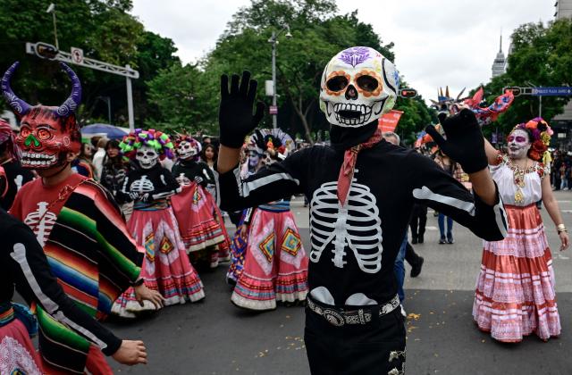 Participants dressed as skeletons take part in the Alebrijes Parade ahead of Day of the Dead celebrations in Mexico City on October 17, 2026. The Alebrijes Parade is an annual event celebrating Mexican folk art and handicrafts, during which giant mythical creatures made of "cartoneria" (a form of papier-mache) are paraded from Mexico City's Zocalo through the capital's main avenues to the Angel of Independence, where they remain on display. (Photo by Alfredo ESTRELLA / AFP)