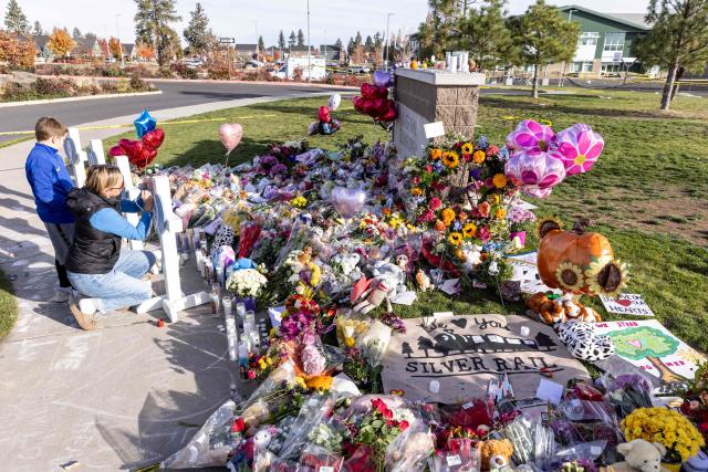People pay their respects at a memorial site outside of Silver Rail Elementary School in Bend, Oregon, on October 17, 2026. Three children and one teacher were shot dead at an elementary school on October 15 in the northwestern US state of Oregon, police said, adding that the assailant was a 16-year-old who was killed by an armed bystander. (Photo by Payton Bruni / AFP)