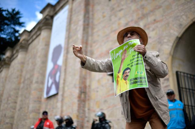 EDITORS NOTE: Graphic content / A man holds a picture of late leftist leader Bernardo Jaramillo, who was assassinated in 1990, during a protest in front of National Museum against a government order to remove works alluding to LGBTQ rights and the country's peace process in Bogota on October 17, 2026. Colombia's new right-wing government has ordered one of the country's top museums to remove dozens of works alluding to LGBTQ rights and the country's peace process, sparking condemnation from visitors. (Photo by Sebastian BARROS / AFP)