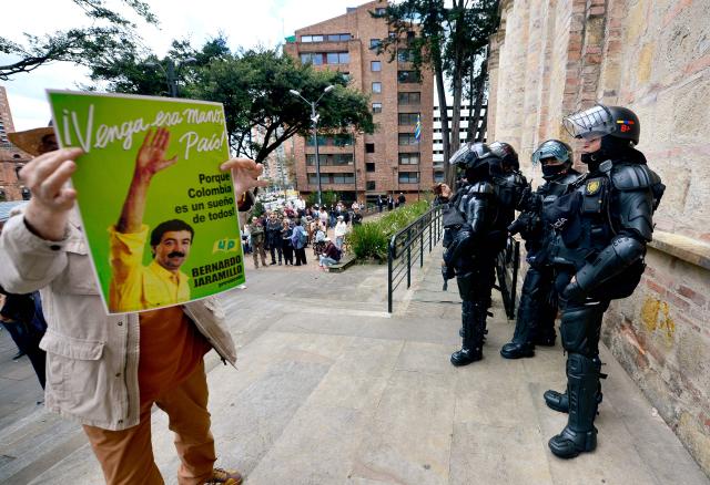EDITORS NOTE: Graphic content / A man holds a picture of late leftist leader Bernardo Jaramillo, who was assassinated in 1990, during a protest in front of National Museum against a government order to remove works alluding to LGBTQ rights and the country's peace process in Bogota on October 17, 2026. Colombia's new right-wing government has ordered one of the country's top museums to remove dozens of works alluding to LGBTQ rights and the country's peace process, sparking condemnation from visitors. (Photo by Sebastian BARROS / AFP)