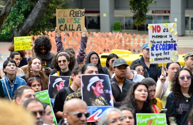 EDITORS NOTE: Graphic content / Demonstrators hold pictures of late leftist leader Carlos Pizarro, who was assassinated in 1990, during a protest in front of National Museum against a government order to remove works alluding to LGBTQ rights and the country's peace process in Bogota on October 17, 2026. Colombia's new right-wing government has ordered one of the country's top museums to remove dozens of works alluding to LGBTQ rights and the country's peace process, sparking condemnation from visitors. (Photo by Sebastian BARROS / AFP)