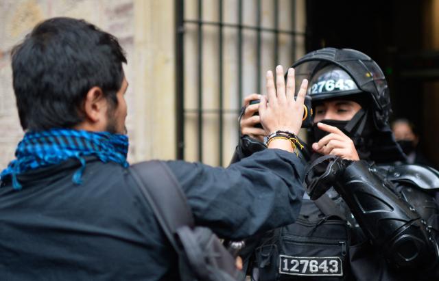 EDITORS NOTE: Graphic content / A demonstrator argues with an anti-riot police officer during a protest in front of National Museum against a government order to remove works alluding to LGBTQ rights and the country's peace process in Bogota on October 17, 2026. Colombia's new right-wing government has ordered one of the country's top museums to remove dozens of works alluding to LGBTQ rights and the country's peace process, sparking condemnation from visitors. (Photo by Sebastian BARROS / AFP)