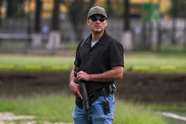 A security officer of Guatemala's Public Ministry stands guard near the body of lawyer Juan Francisco Solorzano Foppa at the Campo Marte sports complex in Guatemala City on October 17, 2026. Former Guatemalan prosecutor who denounced corruption cases and alleged links between gangs and politicians was shot dead in Guatemala City on October 17, 2026, police said. (Photo by Johan ORDONEZ / AFP)