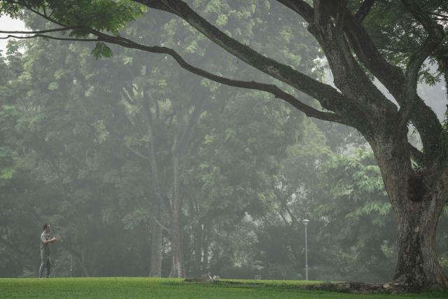 A man exercises in a park in Singapore on October 18, 2026, as the country continues to be shrouded in haze caused by fires in Indonesia. Ongoing fires in Indonesia that have blanketed parts of Southeast Asia with toxic haze have triggered the highest-level alert by the regional bloc's climate and fire monitor. (Photo by Yuichi YAMAZAKI / AFP)