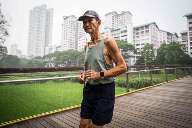 A man jogs past government public housing apartments in Singapore on October 18, 2026, as the country continues to be shrouded in haze caused by fires in Indonesia. Ongoing fires in Indonesia that have blanketed parts of Southeast Asia with toxic haze have triggered the highest-level alert by the regional bloc's climate and fire monitor. (Photo by Yuichi YAMAZAKI / AFP)