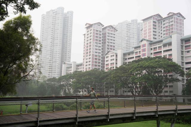 A man wearing a face mask walks past government public housing apartments in Singapore on October 18, 2026, as the country continues to be shrouded in haze caused by fires in Indonesia. Ongoing fires in Indonesia that have blanketed parts of Southeast Asia with toxic haze have triggered the highest-level alert by the regional bloc's climate and fire monitor. (Photo by Yuichi YAMAZAKI / AFP)
