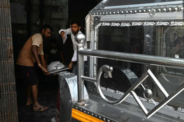 Medical staff carry the body of a victim killed in a stampede during a religious gathering, at a government mortuary in Kolkata on October 18, 2026. At least 17 people were killed and two dozen more injured on October 17 in eastern India after a stampede that was likely caused by sudden rainfall during a Hindu religious gathering, officials said. (Photo by Dibyangshu SARKAR / AFP)