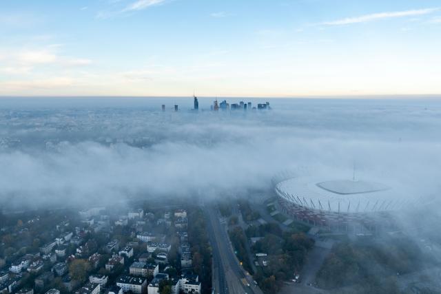 This aerial photograph taken on October 18, 2026 shows Warsaw's skyscrapers and the National Stadium (R) shrouded in a blanket of fog on an autumn morning. (Photo by Sergei GAPON / AFP)