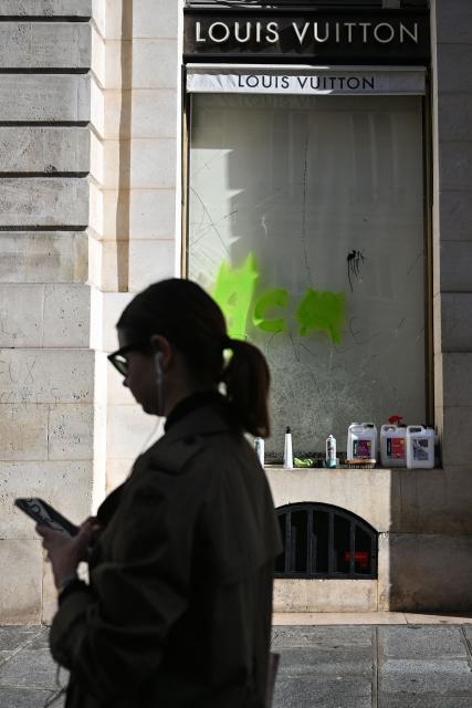 A pedestrian walks past the damaged "Louis Vuitton" shop, in central Paris on October 18, 2026, a day after nationwide protests against the "high cost of living". France's Prime Minister Sebastien Lecornu said 1,200 people were arrested in protests across the country on October 17, and 150 police were hurt as Clashes between police and protesters, massive looting and multiple blazes gripped France as nationwide marches against soaring inflation degenerated into street violence of "extreme intensity". (Photo by Matthieu RONDEL / AFP)
