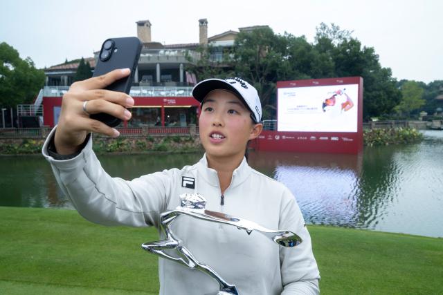 China's Yin Ruoning takes a selfie with the trophy after winning the Buick LPGA Shanghai golf tournament in Shanghai on October 18, 2026. (Photo by CN-STR / AFP) / China OUT