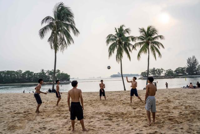 People play beach volleyball at Siloso Beach on Sentosa Island in Singapore on October 18, 2026, as the country continues to be shrouded in haze caused by fires in Indonesia. (Photo by Yuichi YAMAZAKI / AFP)