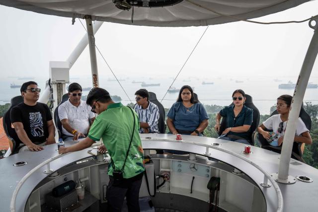 People ride the SkyHelix Sentosa attraction in Singapore on October 18, 2026, as the country continues to be shrouded in haze caused by fires in Indonesia. (Photo by Yuichi YAMAZAKI / AFP)