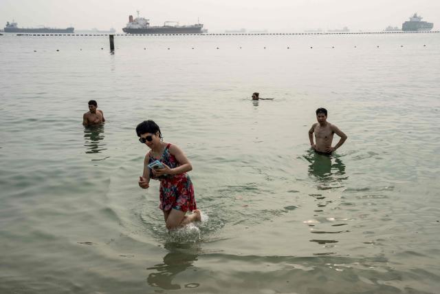 People cool off in the waters off Siloso Beach on Sentosa Island in Singapore on October 18, 2026, as the country continues to be shrouded in haze caused by fires in Indonesia. (Photo by Yuichi YAMAZAKI / AFP)