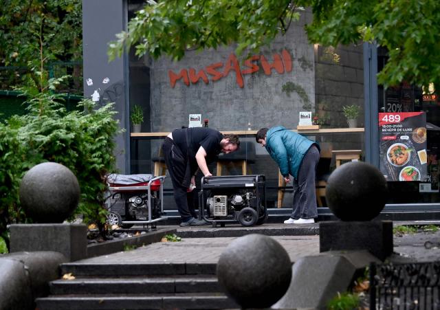 Employees of a Japanese restaurant in Kyiv start power generators during an outage on October 18, 2026, caused by attacks on energy facilities in the country, amid the Russian invasion of Ukraine. (Photo by Sergei SUPINSKY / AFP)