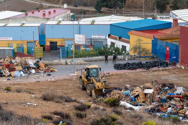 Workers with excavator clear debris from a dismantled migrant settlement at the entrance to the Tarajal warehouses, in Spain's North African enclave of Ceuta on October 18, 2026. Scores of migrants remain sleeping rough in outlying neighborhoods of the city since the massive influx of tens of thousands of migrants from Morocco in late July, fueling tension in this Spanish North African enclave of some 80,000 inhabitants. Migrants are being transported by bus to police facilities, with minors taken to the National Police headquarters and adults transferred to the Tarajal Temporary Assistance Centre for Foreigners (CATE) for identification, registration and screening. (Photo by Antonio Sempere / AFP)
