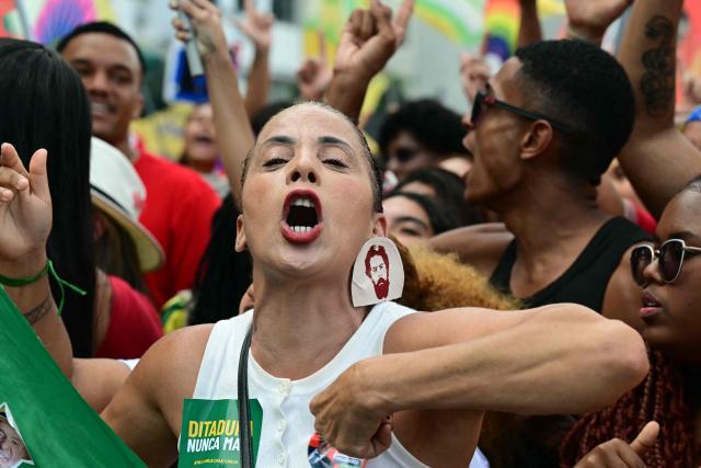 A woman gestures during the "Ato Musical pela Democracia" (Musical Act for Democracy), a concert held in defense of democracy, at Copacabana Beach in Rio de Janeiro, Brazil, on October 18, 2026, one week before the presidential runoff. (Photo by Pablo PORCIUNCULA / AFP)