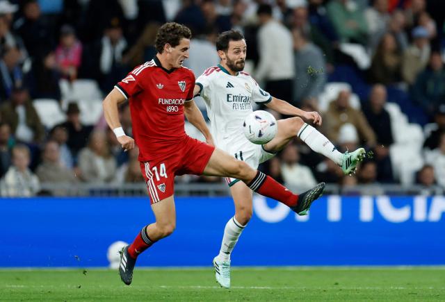 Sevilla's Spanish midfielder #14 Manu Bueno fights for the ball with Real Madrid's Portuguese midfielder #20 Bernardo Silva during the Spanish league football match between Real Madrid CF and Sevilla FC at the Santiago Bernabeu stadium in Madrid on October 18, 2026. (Photo by Oscar DEL POZO / AFP)