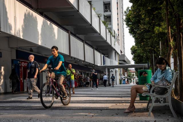 People walk and cycle along a street in Singapore on October 19, 2026, as the country continues to be shrouded in haze caused by fires in Indonesia. (Photo by Yuichi YAMAZAKI / AFP)