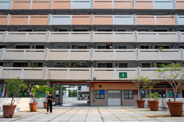 A woman walks past a public housing apartment block in Singapore on October 19, 2026, as the country continues to be shrouded in haze caused by fires in Indonesia. (Photo by Yuichi YAMAZAKI / AFP)