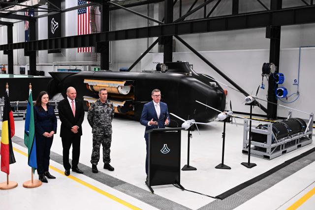 Australia’s Minister for Defence Industry Pat Conroy (R) speaks to the media alongside Australia’s Chief Defence Scientist Tanya Monro (L), Anduril Australia & Asia Pacific CEO and Executive Chairman David Goodrich (2nd L), and Royal Australian Navy Chief of Navy Vice Admiral Matthew Buckley in front of the Ghost Shark autonomous undersea vehicles at an Anduril facility in Sydney on October 19, 2026, during the unveiling of three new autonomous systems capabilities under AUKUS Pillar II. (Photo by Saeed KHAN / AFP)