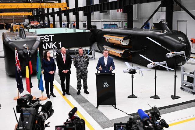 Australia’s Minister for Defence Industry Pat Conroy (R) speaks to the media alongside Australia’s Chief Defence Scientist Tanya Monro (L), Anduril Australia & Asia Pacific CEO and Executive Chairman David Goodrich (2nd L), and Royal Australian Navy Chief of Navy Vice Admiral Matthew Buckley in front of the Ghost Shark autonomous undersea vehicles at an Anduril facility in Sydney on October 19, 2026, during the unveiling of three new autonomous systems capabilities under AUKUS Pillar II. (Photo by Saeed KHAN / AFP)