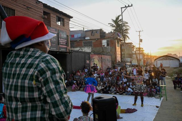 People watch a performance by members of the TET Center for Artistic Creation during the 6th Social Festival of Performing Arts in Playa Verde, Catia La Mar, La Guaira state, Venezuela, on October 18, 2026. The TET Center for Artistic Creation perform for survivors of two June 24, 2026, devastating earthquakes which killed more than 6,500 people. (Photo by Federico PARRA / AFP)