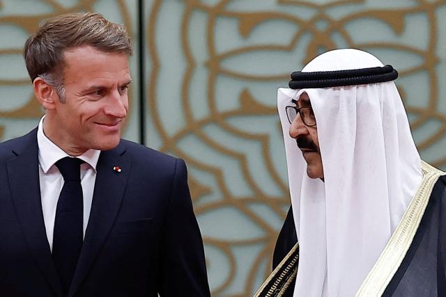 French President Emmanuel Macron (L) looks over at the Emir of Kuwait Sheikh Mishal Al-Ahmad Al-Jaber Al-Sabah during a welcoming ceremony upon the president's arrival at Kuwait International Airport, in Kuwait City October 19, 2026. (Photo by Benoit Tessier / POOL / AFP)
