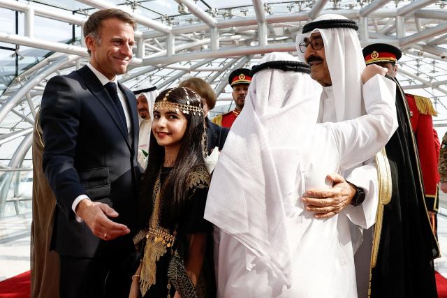 French President Emmanuel Macron (L) and the Emir of Kuwait Sheikh Mishal Al-Ahmad Al-Jaber Al-Sabah are greeted by children during a welcoming ceremony upon the president's arrival at Kuwait International Airport, in Kuwait City October 19, 2026. (Photo by Benoit Tessier / POOL / AFP)