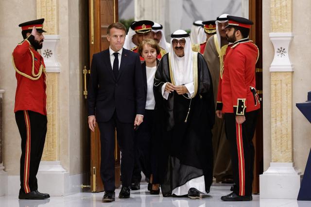 French President Emmanuel Macron (L) and the Emir of Kuwait Sheikh Meshal Al-Ahmad Al-Jaber Al-Sabah walk through a door at the Bayan Palace in Kuwait City on October 19, 2026. The French president arrived in Kuwait on October 19, beginning a tour of four Gulf countries, Kuwait, UAE, Bahrain and Qatar. (Photo by Benoit Tessier / POOL / AFP)