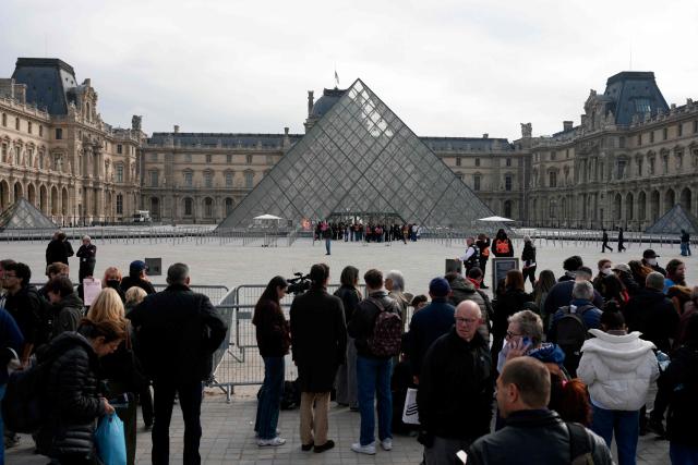 Visitors wait outside a cordonned-off area as protesters, including students from the Ecole du Louvre, block the entrance to the Louvre Museum to express their “support” for the high school students’ movement and to denounce police repression in Paris on October 19, 2026, two days after riots and looting occurred on the sidelines of nationwide cost-of-living demonstrations. French authorities scrambled to stem public discontent fuelling mass demonstrations that over the weekend spilled over into some of the worst street violence in recent years. Some half a million people turned out across France to protest the surging cost of living, a culmination of four weeks of protests that began with high school students demanding better conditions at their schools. (Photo by Dimitar DILKOFF / AFP)