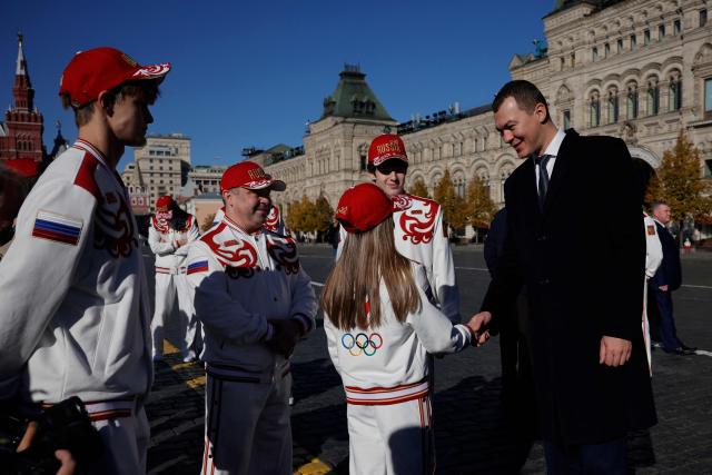 Russian Sports Minister Mikhail Degtyarev, Russian athletes, who will participate in the Dakar 2026 Youth Olympic Games, and sports officials interact on Red Square after getting official outfits at the Bosco equipment center in Moscow on October 19, 2026. (Photo by TATYANA MAKEYEVA / AFP)