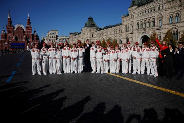 Russian Sports Minister Mikhail Degtyarev, Russian athletes, who will participate in the Dakar 2026 Youth Olympic Games, and sports officials pose on Red Square after getting official outfits at the Bosco equipment center in Moscow on October 19, 2026. (Photo by TATYANA MAKEYEVA / AFP)