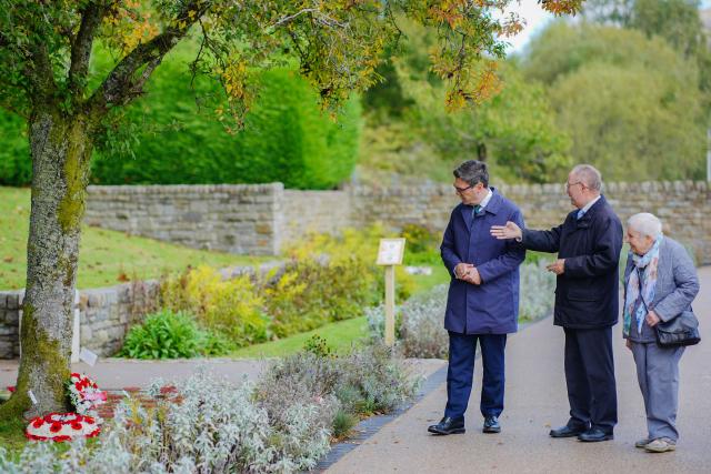 Britain's Prime Minister Andy Burnham (L) with Chairman of the Aberfan Memorial Charity David Davies (2R) and Mair Morgan (R) who is the last surviving teacher of Pantglas Junior School who witnessed the Aberfan disaster, during a visit to the Aberfan memorial garden in Aberfan, south Wales on October 19, 2026, to pay their respects to those who lost their lives during the Aberfan disaster on October 21, 1966. The garden sits on the site of the Pantglas school which was tragically destroyed in a coal-tip landslide on 21st October 1966. The incident led to the loss of 144 lives, including 116 children. (Photo by Ben Birchall / POOL / AFP)