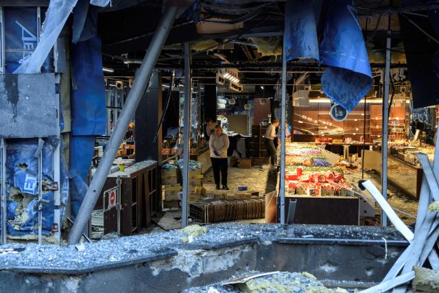 People clear debris in a damaged shopping mall following an air strike on Kyiv on October 19, 2026, amid the Russian invasion of Ukraine. (Photo by Vladyslav Musiienko / AFP)