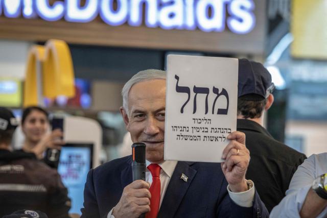 Israeli Prime Minister Benjamin Netanyahu holds up an enlarged copy of a Likud party ballot as he meets with voters at a mall in Ramle on October 19, 2026. Israel heads to the polls on October 27 in its first election since the October 7, 2023 Hamas-led attack, in what is seen as a referendum on the prime minister. (Photo by ilia YEFIMOVICH / AFP)