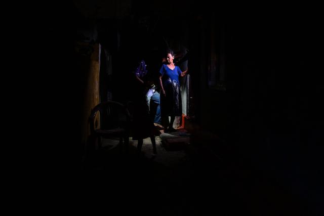 Residents use a mobile torchlight at their house in Colombo on October 19, 2026 during a power outage as part of Sri Lanka's electricity rationing measure, two days after a nationwide blackout. Sri Lanka announced nationwide electricity rationing from October 19, two days after a complete breakdown of the national grid caused by a fault at a coal-fired generator. The state-run electricity utility said power would be cut for one hour in stages across the island during a four-hour period from October 19 evening. (Photo by Ishara S. KODIKARA / AFP)