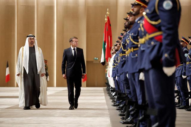 UAE President Sheikh Mohamed bin Zayed Al-Nahyan (L) and France's President Emmanuel Macron (C) inspect an honour guard during a reception ceremony at Abu Dhabi International Airport in Abu Dhabi on October 19, 2026. Macron began a Gulf tour on October 19 aimed at securing oil and diesel supplies in an effort to bring down prices, after a weekend of violent protests sparked by soaring living costs. (Photo by Benoit Tessier / POOL / AFP)